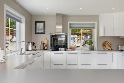 a kitchen with white cabinets and a sink at Grand and modern cabin in Sogndal