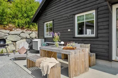 a patio with a table and chairs and a house at Grand and modern cabin in Sogndal