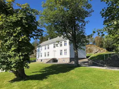 a large white house with trees in the grass at Storlauvøya The Atlantic Ocean Road in Karvåg