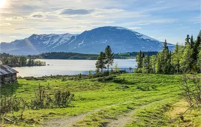 a field with a mountain and a body of water at Nice Home In Hemsedal With Sauna in Hemsedal