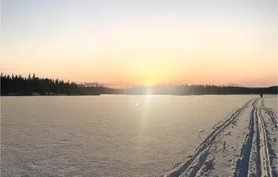 a snow covered field with the sun setting over the water at Nice Home In Hemsedal With Sauna in Hemsedal
