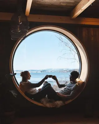a man and a woman sitting in a round window at Fuglekassehytta in Sparbu