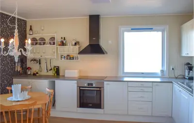 a kitchen with white cabinets and a table and a window at Stunning Home In Skånevik With Kitchen in Skånevik