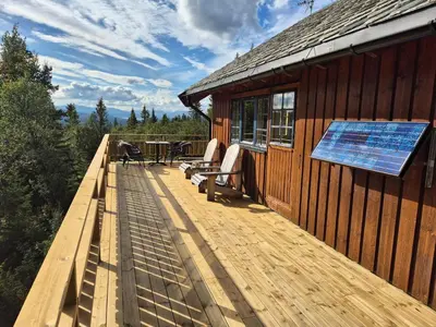 a deck with a solar panel on the side of a house at Cozy log cabin at beautiful Nystølsfjellet in Gol
