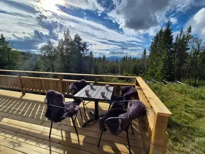 a table and chairs on a wooden deck at Cozy log cabin at beautiful Nystølsfjellet in Gol