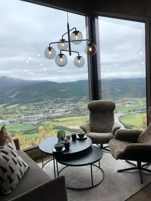 a living room with a chandelier and a table and chairs at Baugsberget Fjelltopphytter in Alvdal