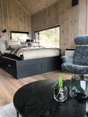 a bedroom with a bed and a chair and a table at Baugsberget Fjelltopphytter in Alvdal