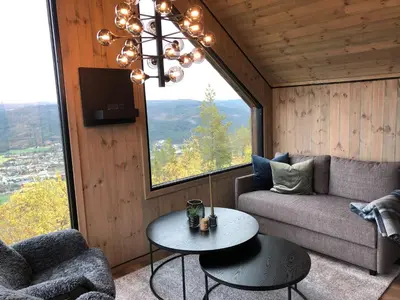 a living room with a couch and a table and a window at Baugsberget Fjelltopphytter in Alvdal