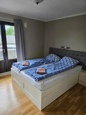 a bedroom with a bed with blue comforter and a window at Florvåg -flott utsikt mot byen in Florvåg
