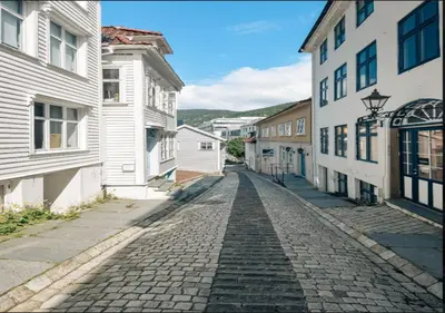 a cobblestone street in a town with white buildings at Bergen city center apartment in Bergen