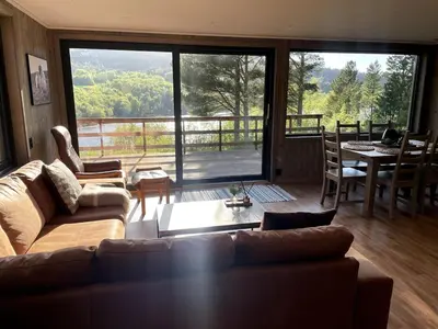 a living room with a couch and a large window at A cottage by the forest with a sea view ! in Søfstad