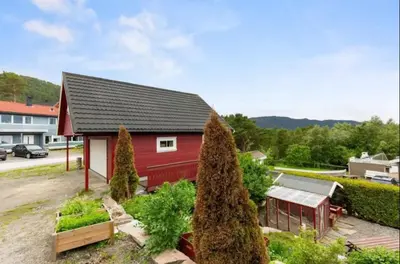 a red house with a black roof and some trees at Leilighet med gratis parkering og WiFi in Kristiansund