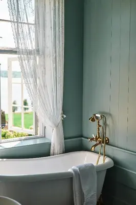 a bath tub in a bathroom with a window at Hoel Gård - Herregården ved Mjøsa in Nes i Ådal