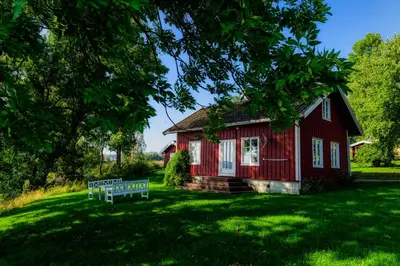 a red house with a bench in front of it at Hoel Gård - Herregården ved Mjøsa in Nes i Ådal