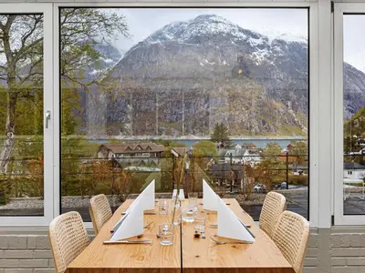 a wooden table with chairs and a mountain view at Eidfjord Hotel in Eidfjord