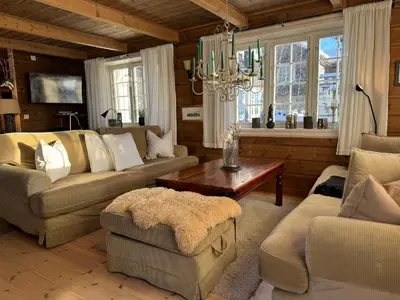 a living room with couches and a table and windows at Bjødnabakkens historie in Beitostøl