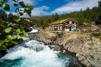 a house on the side of a river at Billingen Seterpensjonat in Skjåk
