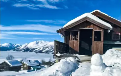 a cabin covered in snow with mountains in the background at 2 Bedroom Stunning Home In Rauland in Rauland