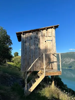 a wooden out house on the side of a lake at Raaum Gard, hytte 2 in Hafslo