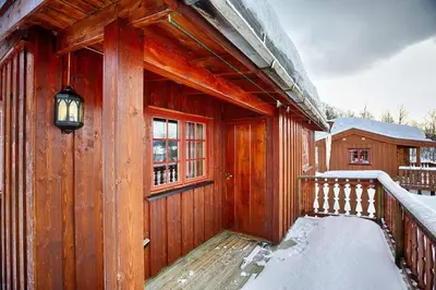 a wooden cabin with a balcony in the snow at Kvetos fjellgårdsutsikt in Beitostøl