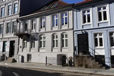 a white building with a black door on a street at Dinbnb Apartments I Charming 3-Bedroom in the Heart of the City in Bergen