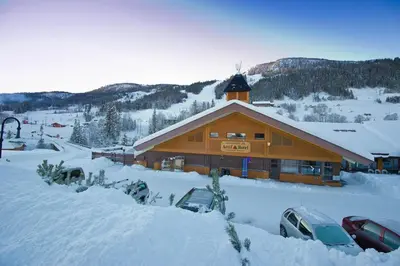 a ski lodge with cars parked in the snow at Actif 106 - Hallingheim apartment ski inn/ski ut in Ål
