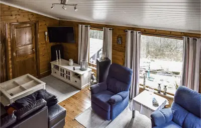 a living room with two blue chairs and a tv at Stunning Home In Førde I Hordaland in Lier