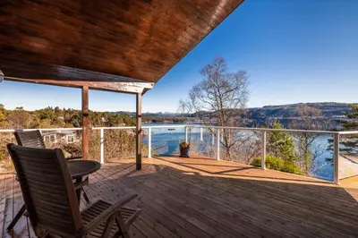 a deck with chairs and a view of the water at Villa Arboretet - Seaside villa with private pool & infrared sauna in the heart of Arboretet, Bergen in Bergen