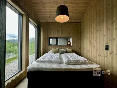 a bedroom with a large bed in a room with windows at Brand new cabin on the sunny side of Gaustatoppen with a beautiful view in Tuddal