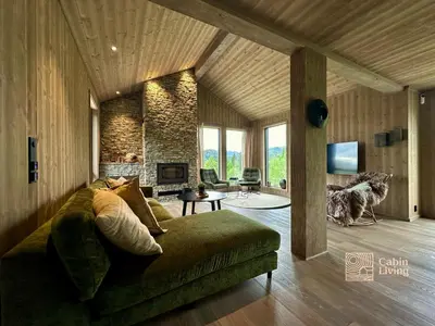 a living room with a couch and a stone wall at Brand new cabin on the sunny side of Gaustatoppen with a beautiful view in Tuddal