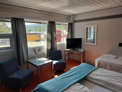 a bedroom with a bed and a desk and a tv at Øiseth Hotell AS in Rendalen
