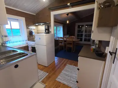 a kitchen with a refrigerator and a dining room at Gaulabua - cozy cabin by the river Gaula in Haltdalen