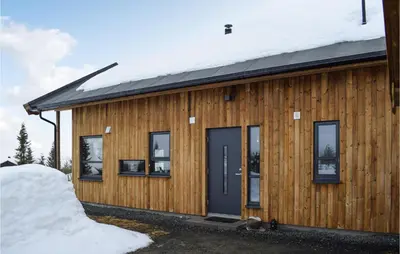 a wooden house with a blue door in the snow at Awesome Home In Rauland With Sauna in Rauland