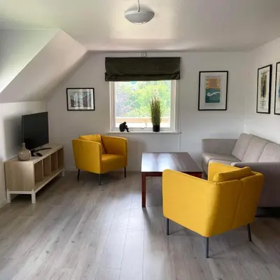 a living room with yellow chairs and a couch at Store Ringheim Apartment - Villa Hjadlane in Vossevangen