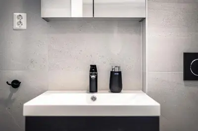 a white sink with a black bottle on top of it at Meltzers Apartments in Bergen