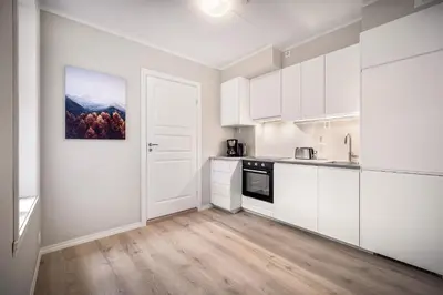 an empty kitchen with white cabinets and wood floors at Meltzers Apartments in Bergen