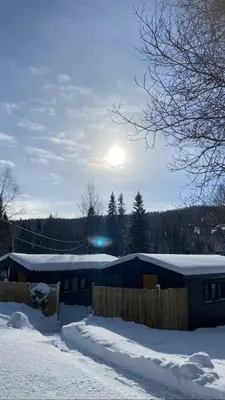 a house in the snow with the sun in the background at Ådalsvollen Retreat in Verdal