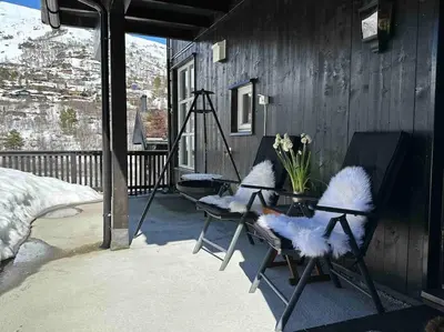 two chairs sitting on a porch with a table and flowers at Lovise Mountain Apartment in Stranda