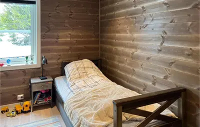 a bed in a room with a wooden wall at Amazing Home In Øyer With Sauna in Øyer