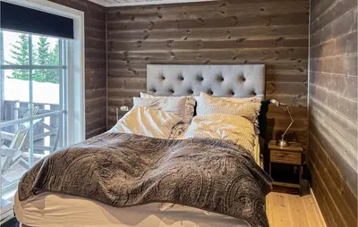 a bedroom with a bed and a wooden wall at Amazing Home In Øyer With Sauna in Øyer