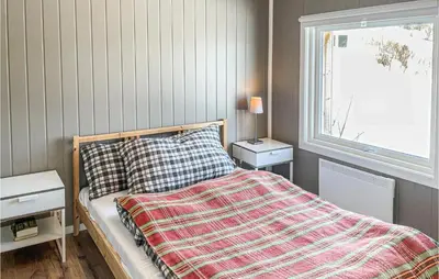 a bedroom with a bed with a striped comforter and a window at Stunning Home In Ålen in Ålen