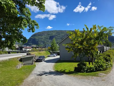 a house on the side of a road with a tree at Rom 4 i bufellesskap in Sogndal