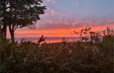 a sunset over a field with a tree in the foreground at Gorgeous Apartment In Espedalen in Espedalen