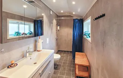 a bathroom with a sink and a toilet and a mirror at Beautiful Home In Vallavik With Kitchen in Djønno