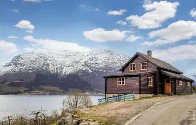 a house on the side of a lake with a mountain at Beautiful Home In Vallavik With Kitchen in Djønno