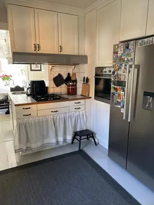a kitchen with a stainless steel refrigerator and a stool at Sandstad, Lilleby i Trondheim in Trondheim
